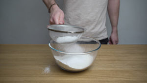 sieving flour into a bowl