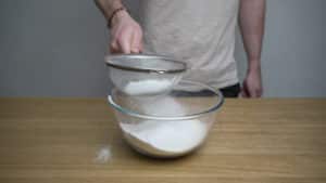 sieving flour into a bowl