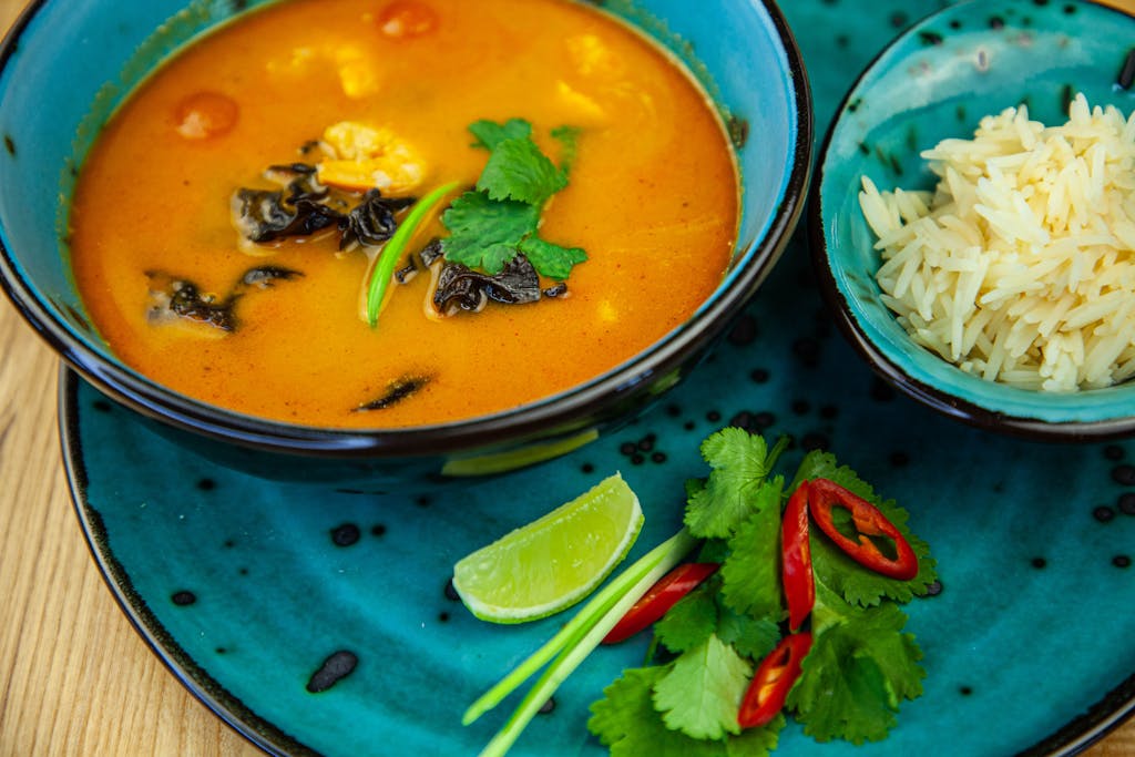 Thai curry with rice, lime, and chili on a turquoise plate, perfect for food lovers.